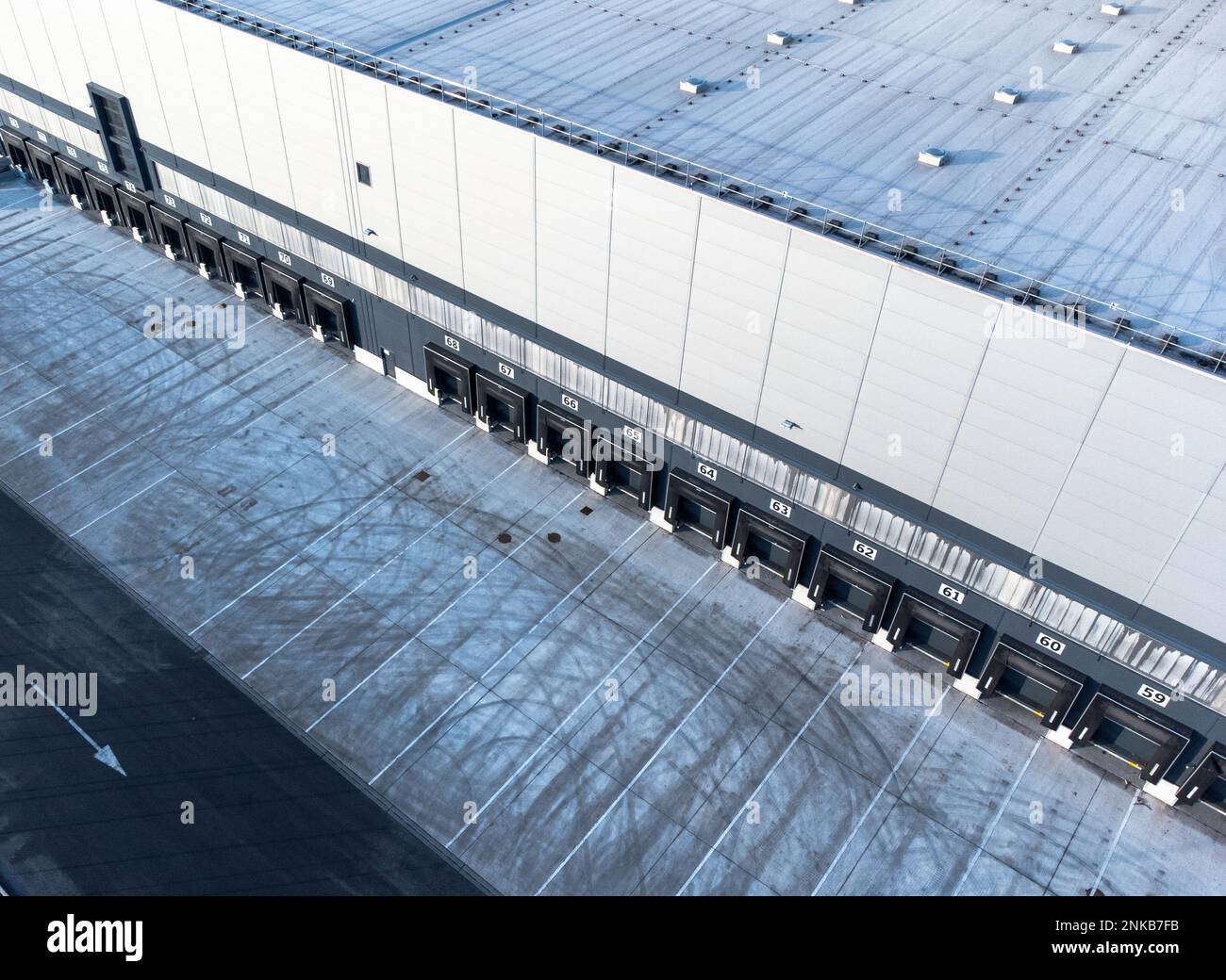 Large distribution warehouse exterior with loading ramp aerial top down