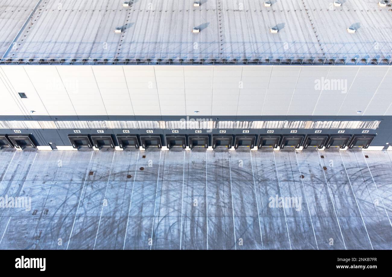 Large distribution warehouse exterior with loading ramp aerial top down