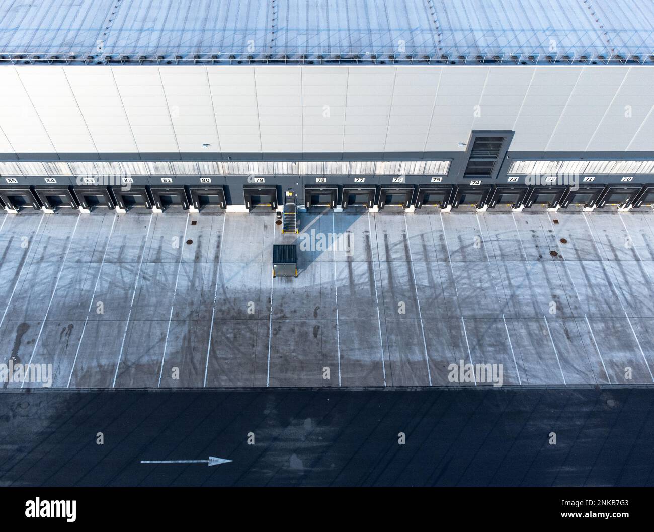 Large distribution warehouse exterior with loading ramp aerial top down