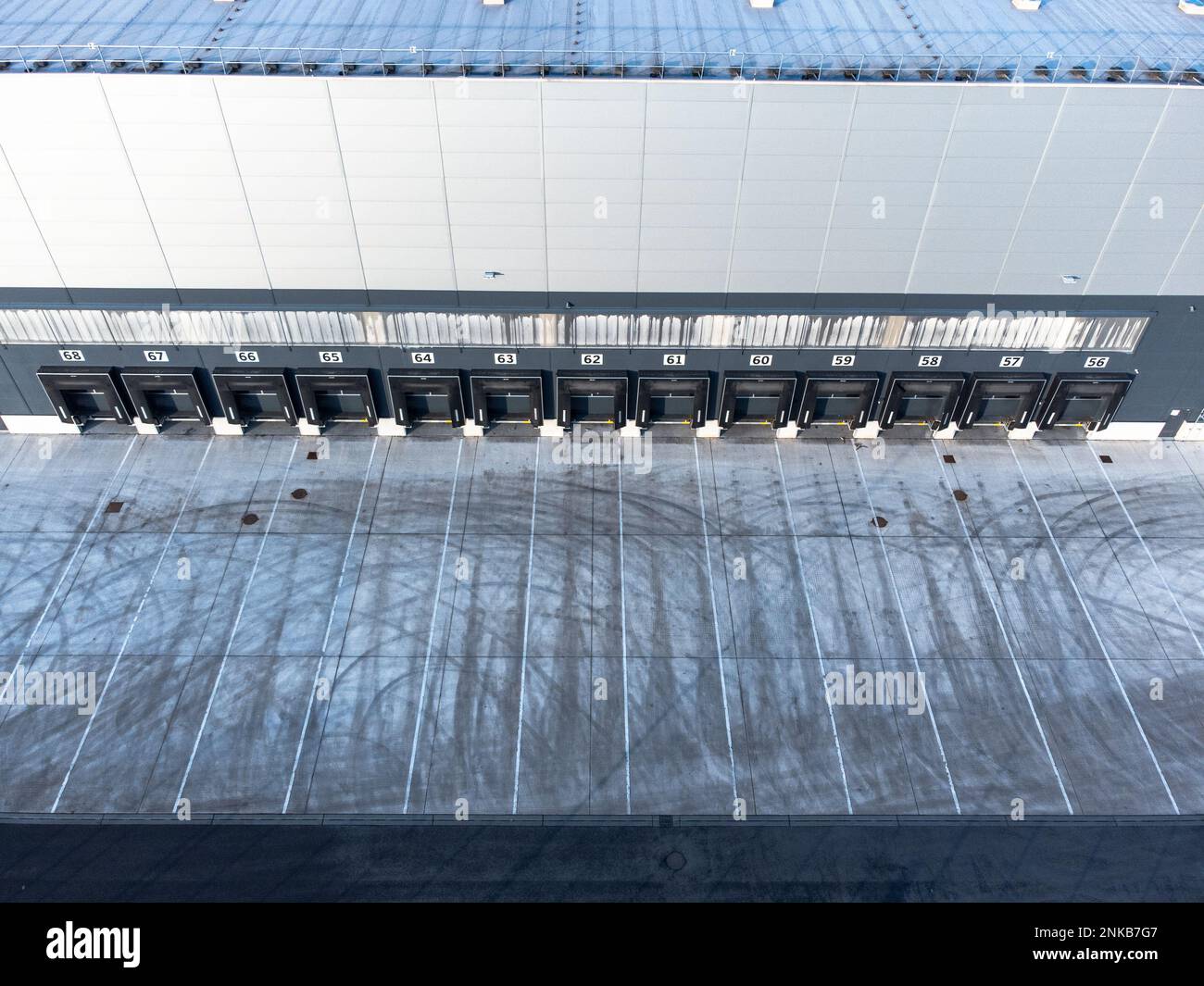 Large distribution warehouse exterior with loading ramp aerial top down