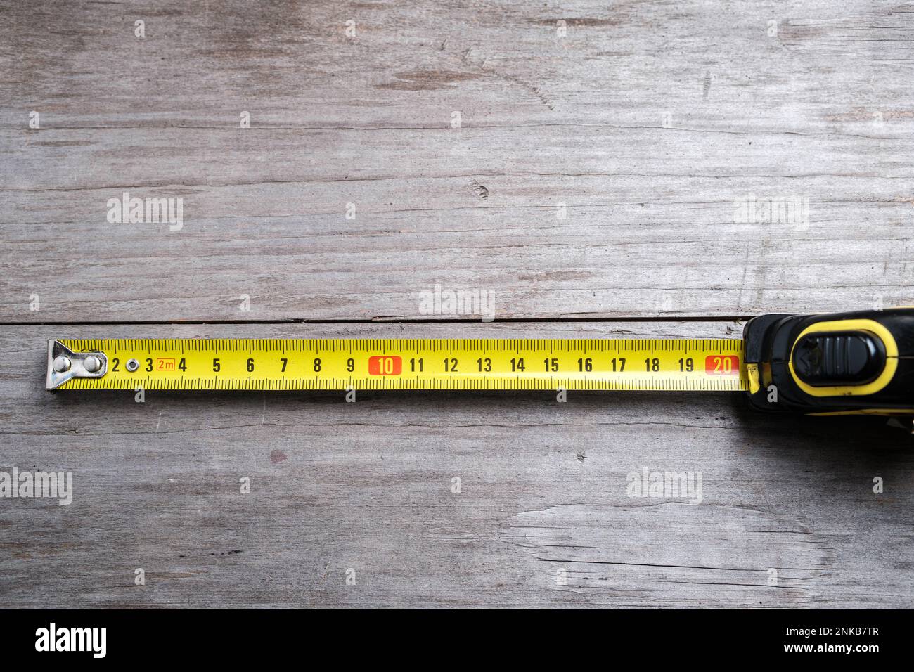 Measuring tape stretched 21 cm on a wooden background. Close-up. Selective focus. Stock Photo