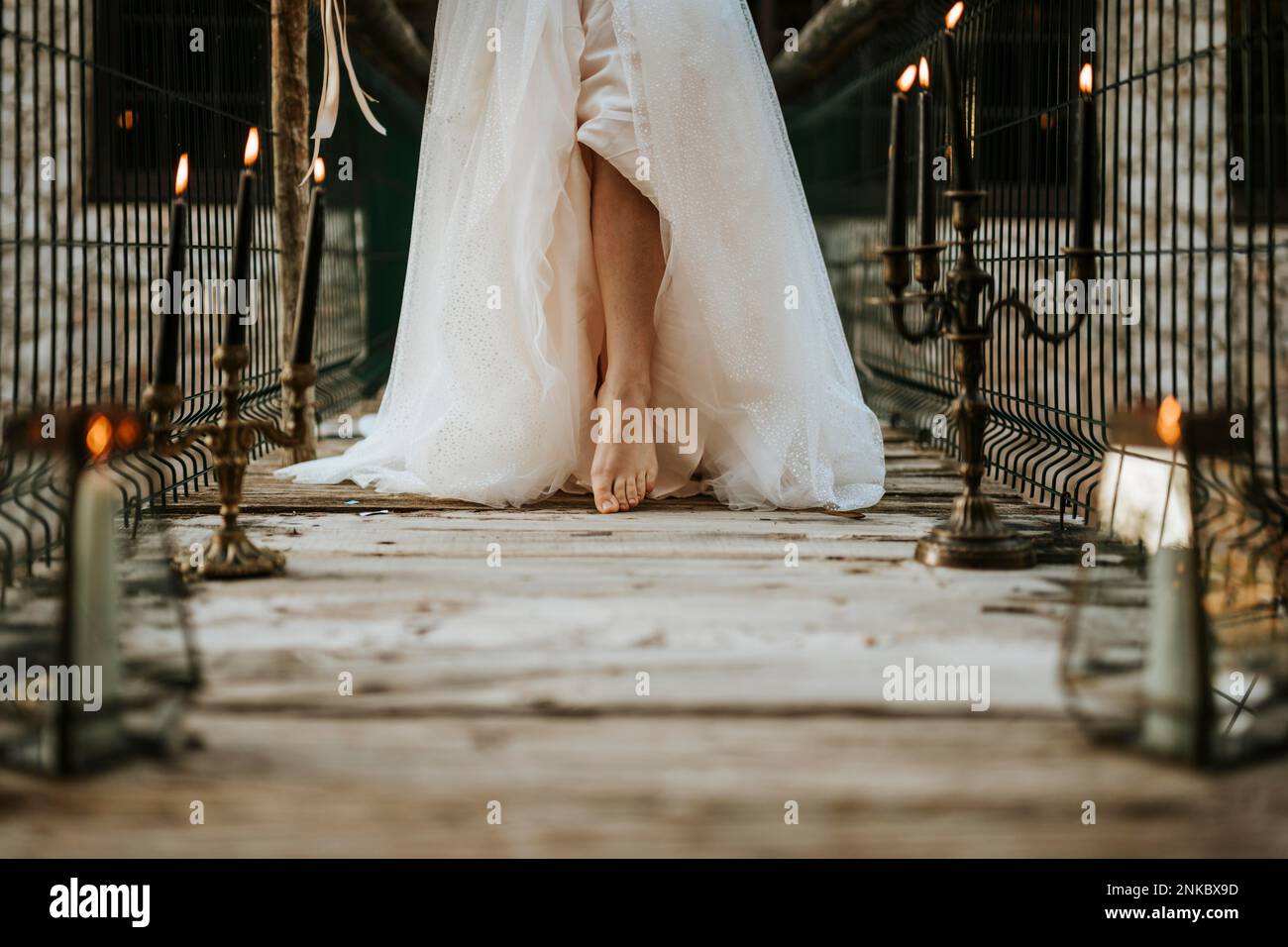 Leg of bride on wooden bridge full of candles Stock Photo