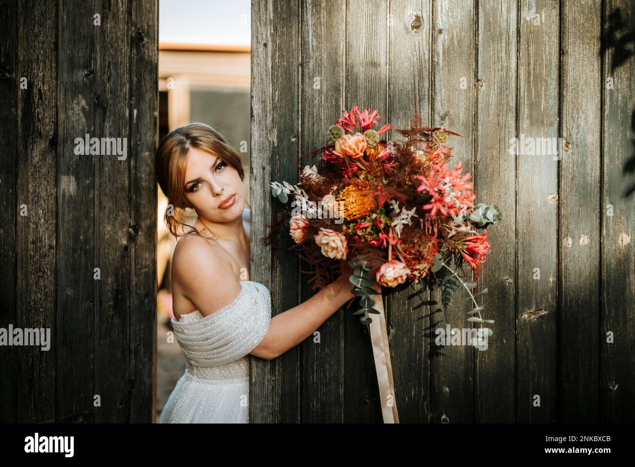 Beautiful bride with a bouquet with wooden door background as a background Stock Photo
