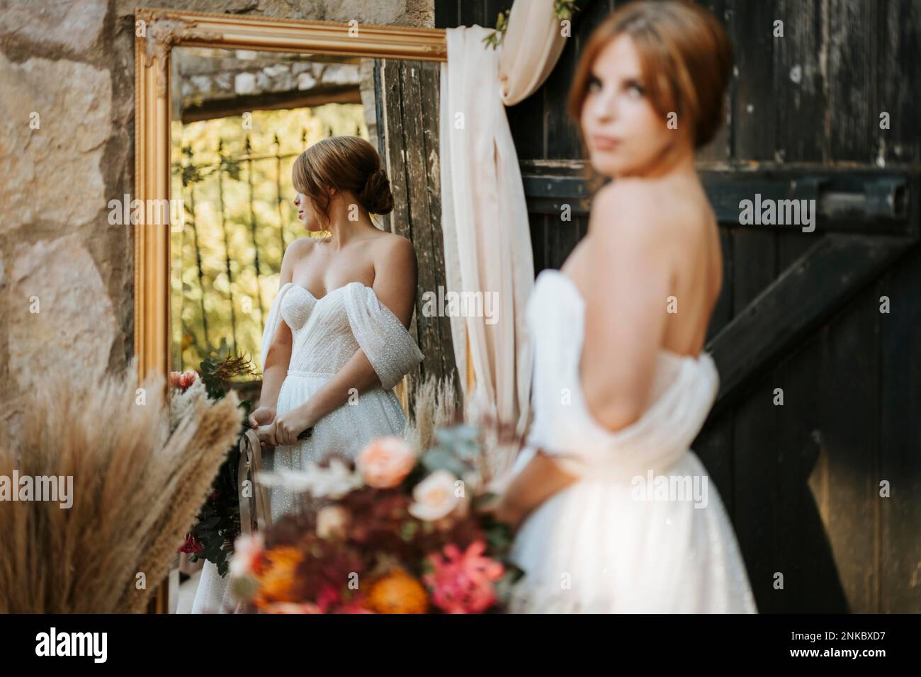 Beautiful bride in rustic arrangement, vintage mirror, wooden door Stock Photo