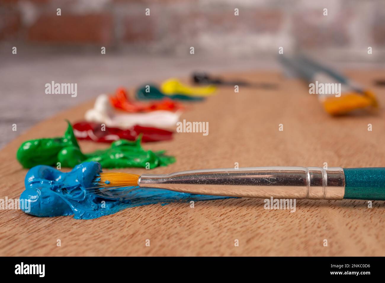 Close-up brush with out-of-focus oil paint colors on a wooden palette Stock Photo