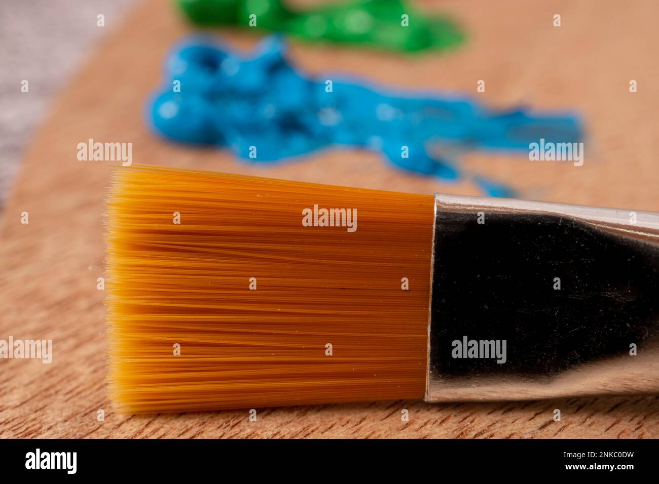Close-up brush with out-of-focus oil paint colors on a wooden palette Stock Photo