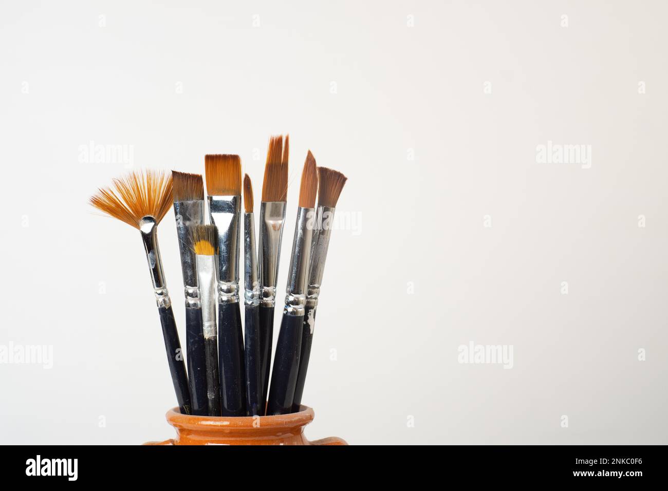 Earthenware jar with brushes isolated on a white background Stock Photo
