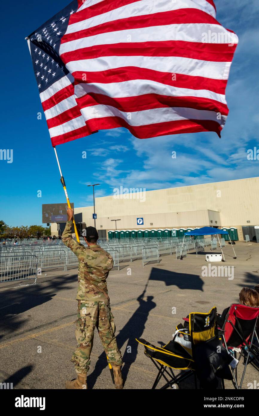 1 October 2022, A man in military clothing waves an American flag outside a Donald Trump, Warren, Michigan, USA Stock Photo