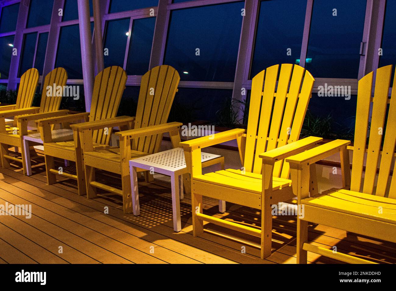 A row of yellow deck chairs at night aboard the Allure of the Seas, Royal Caribbean cruise lines. Stock Photo