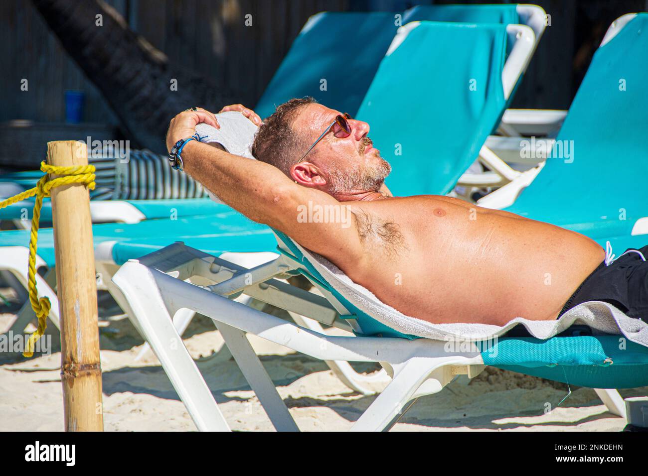 A middle-aged, caucasian man wearing glasses stretched out on a lounge chair, Roatan, Honduras. Stock Photo