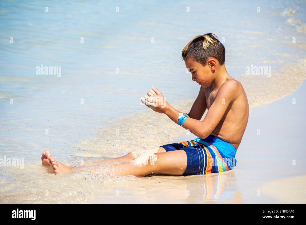 A child playing in the sand on a beach, Roatan, Honduras. Stock Photo