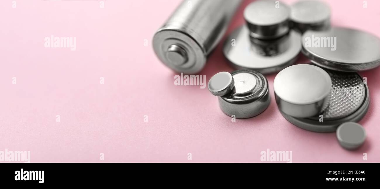 Different batteries on pink background, closeup. Banner for design Stock Photo