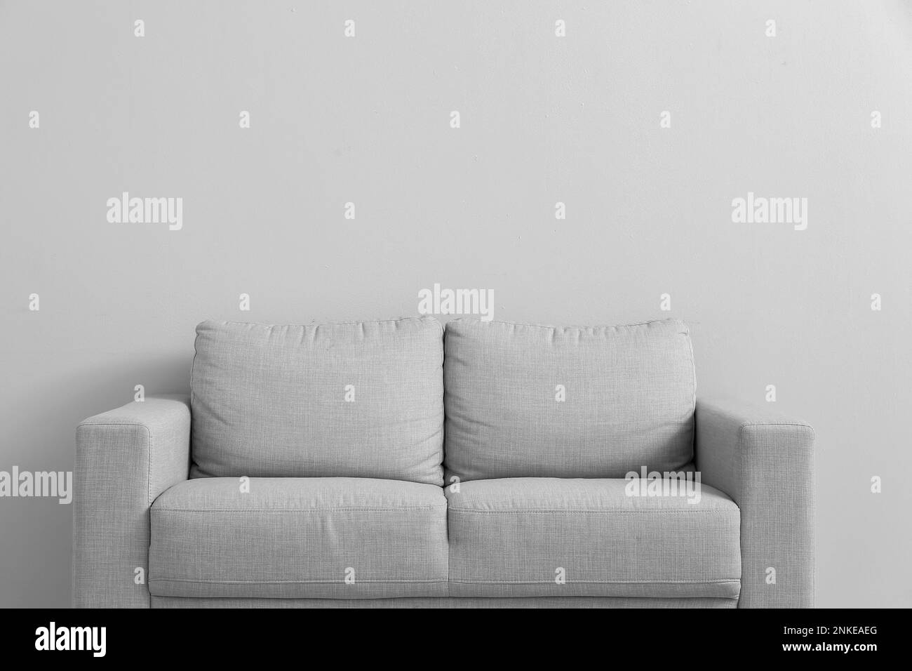 Stylish grey sofa near white wall Stock Photo Alamy