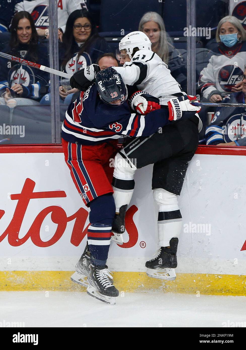 Winnipeg Jets' Zach Sanford (13) and Los Angeles Kings' Troy Stecher (51)  collide during the second period of an NHL hockey game Saturday, April 2,  2022, in Winnipeg, Manitoba. (John Woods/The Canadian