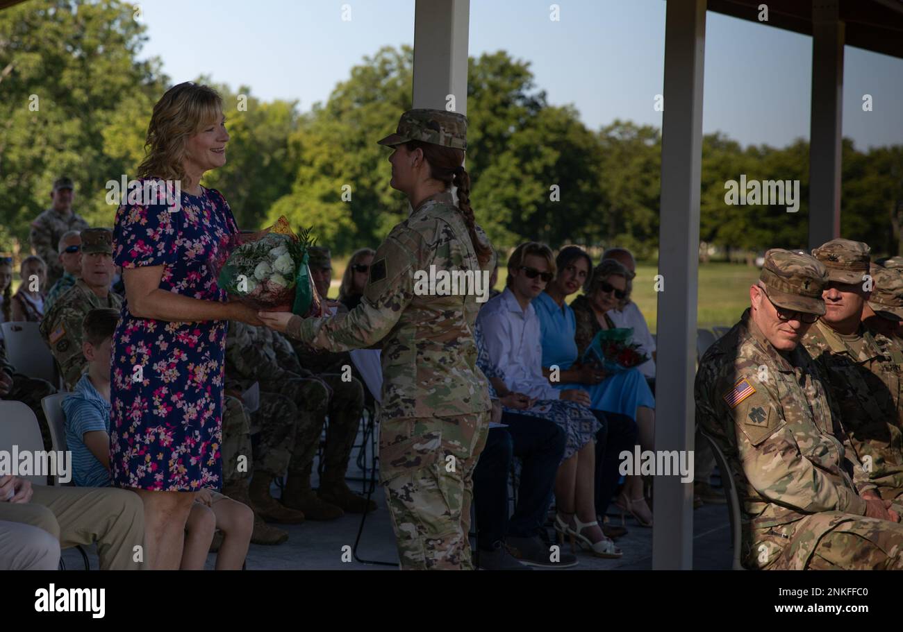 A Soldier from the 45th Infantry Brigade Combat Team presents Bridget Ballenger, wife of incoming commander Col. Andrew Ballenger, with a bouquet of white roses on behalf of the unit as a token of welcome and gratitude at the change of command ceremony, Camp Gruber Training Center, Oklahoma, Aug. 14, 2022. Ballenger has served in the Army National Guard for over 30 years and has received many awards, to include a Legion of Merit and two Bronze Star Medals. (Oklahoma Army National Guard photo by Spc. Danielle Rayon) Stock Photo