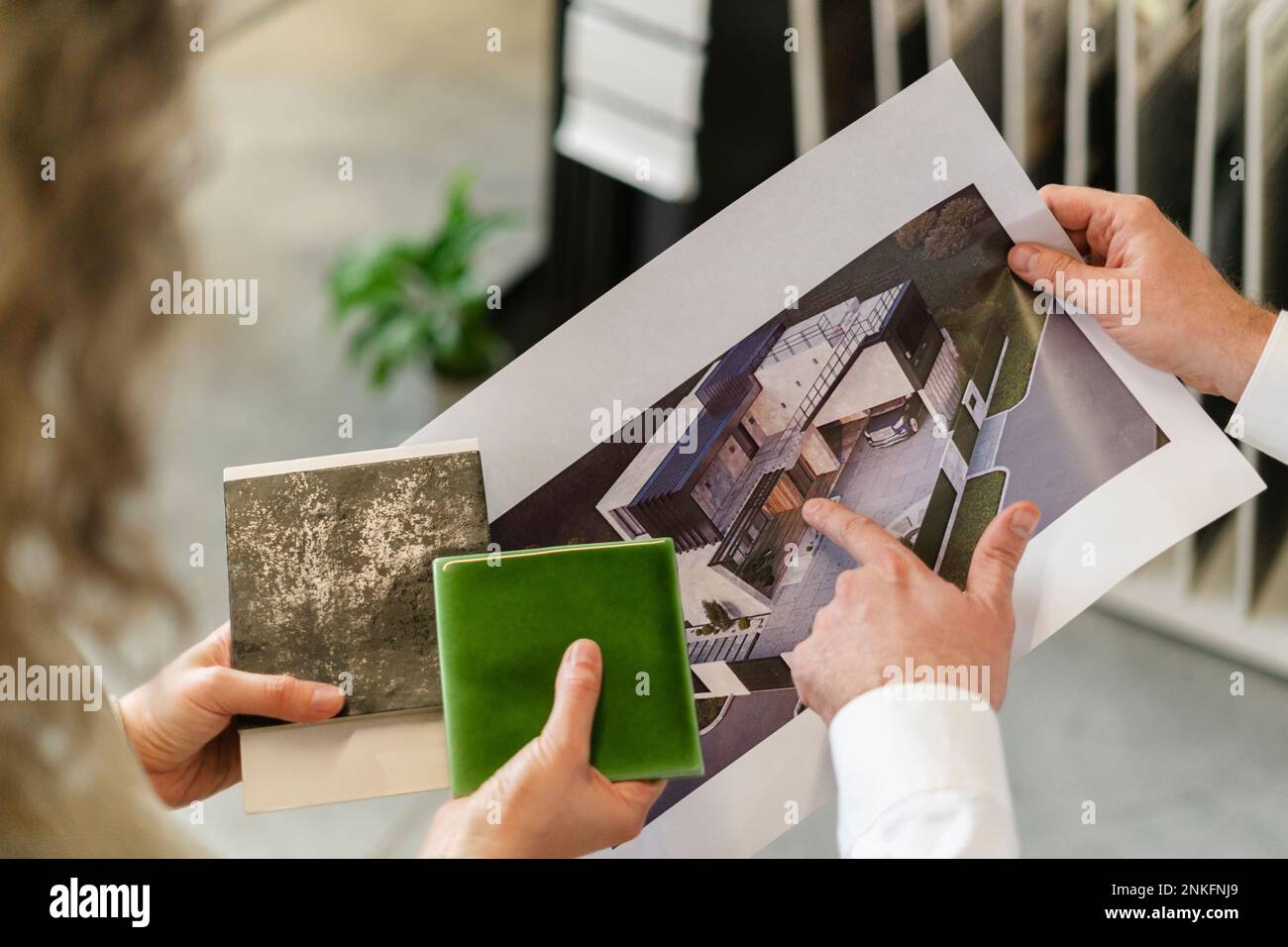 Two colleagues holding printout of a house and tile samples in