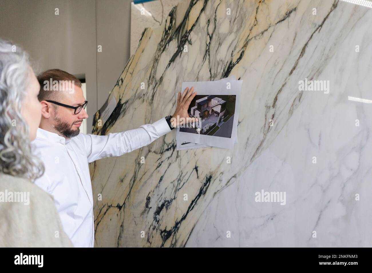 Two architects looking at printout of a house on marble plate Stock Photo