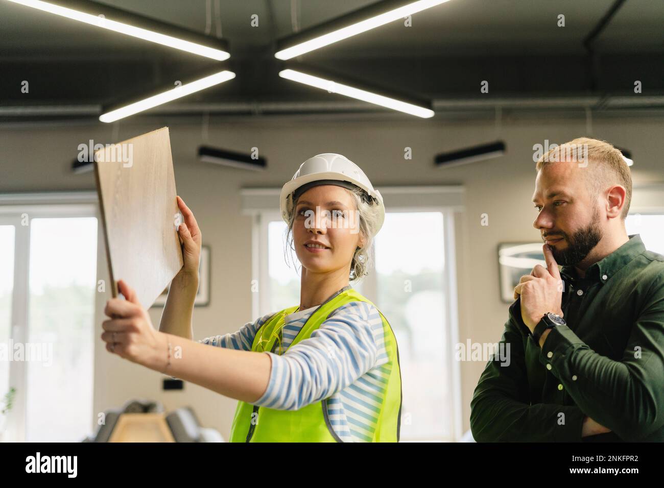 Businessman and engineer examining wooden board in office Stock Photo