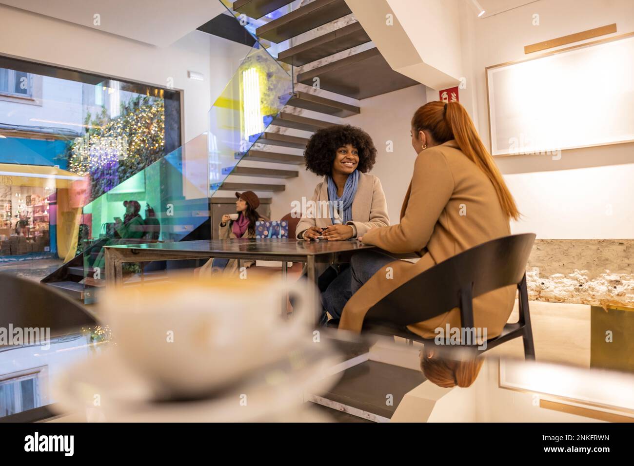 Happy friends sitting at table in cafe Stock Photo