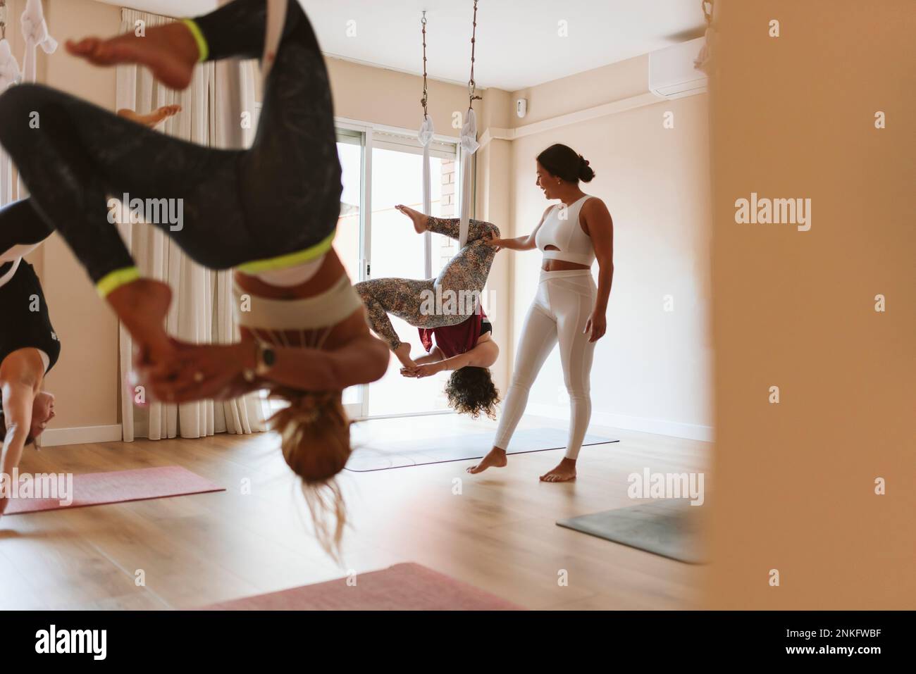 Instructor teaching aerial yoga to students in studio Stock Photo