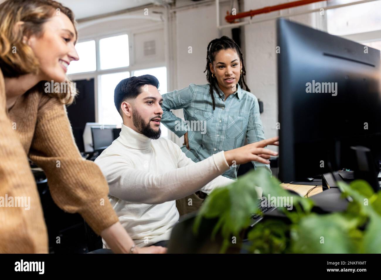 Young businessman explaining colleagues using desktop PC at office Stock Photo