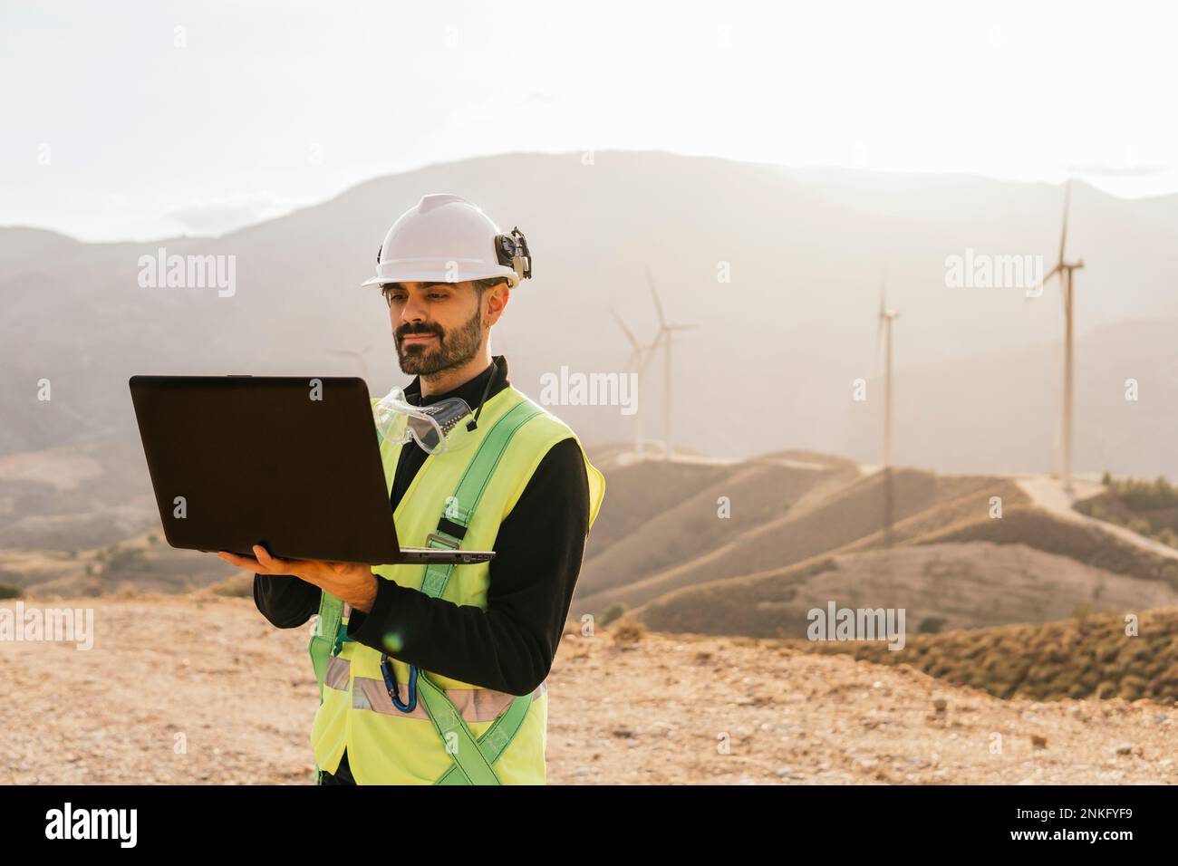 Technician using laptop in front of mountain Stock Photo