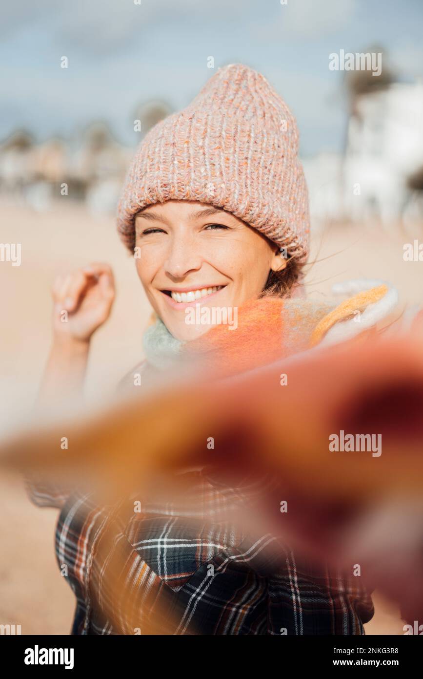 Cheerful woman wearing knit hat at beach Stock Photo