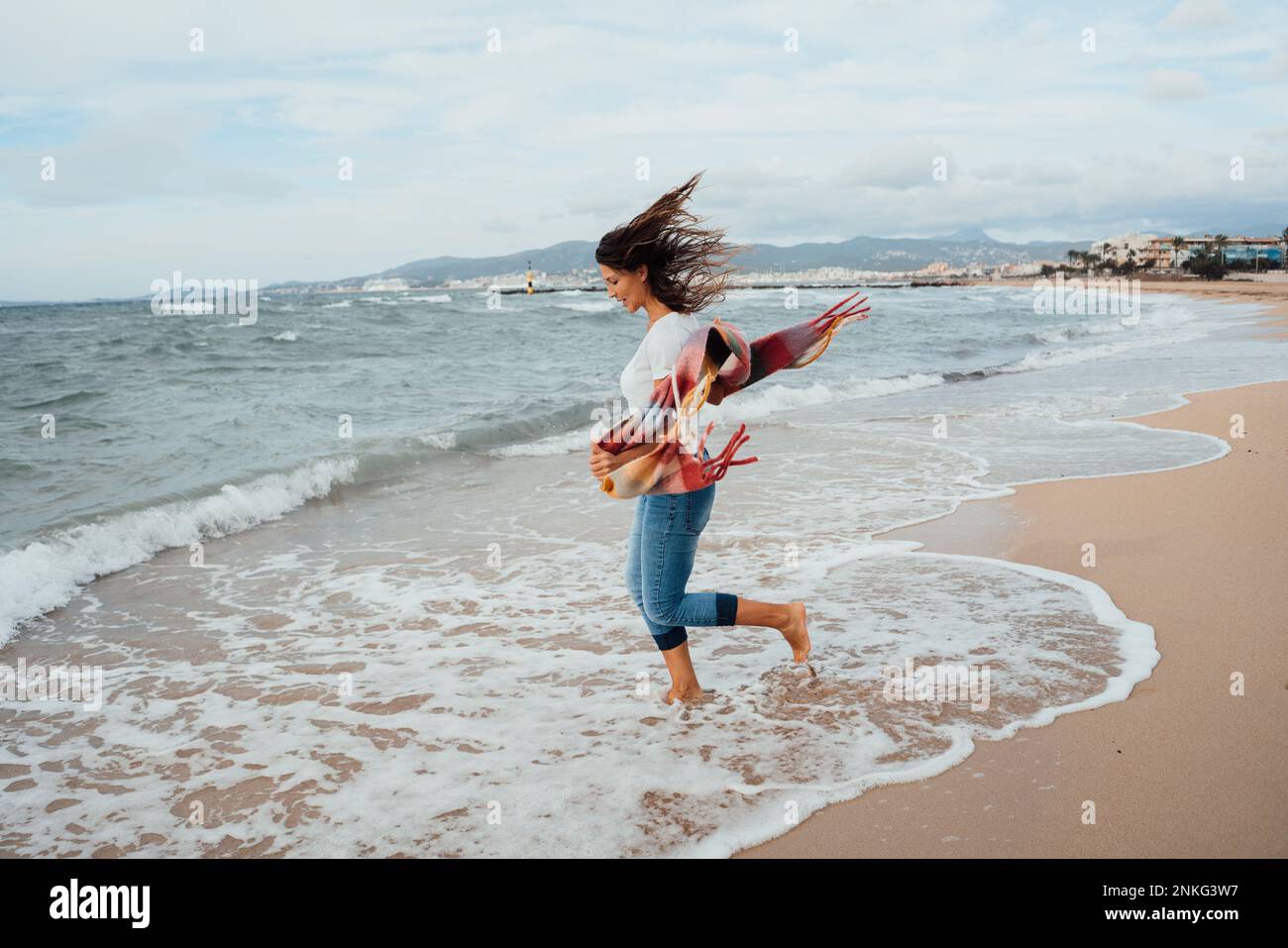 Woman running near waves at beach Stock Photo