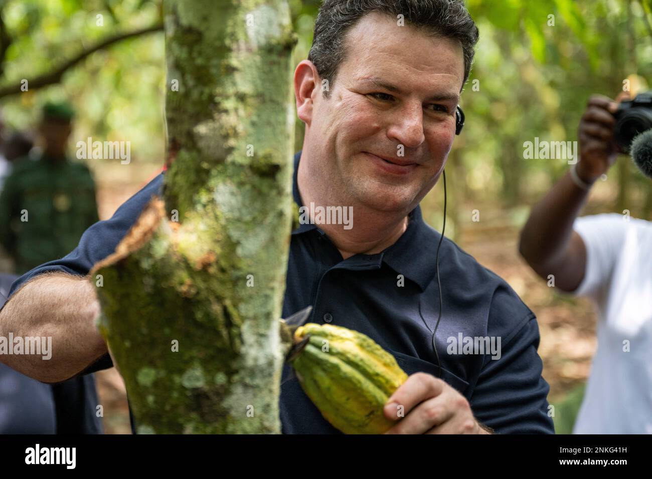 Agboville, Ivory Coast. 23rd Feb, 2023. Hubertus Heil (SPD), Federal Minister of Labor and Social Affairs, harvests a ripe cocoa pod on a cocoa plantation. Federal Minister of Labor Heil and Federal Minister for Economic Cooperation and Development Schulze visit Ghana and the Ivory Coast. Credit: Christophe Gateau/dpa/Alamy Live News Stock Photo