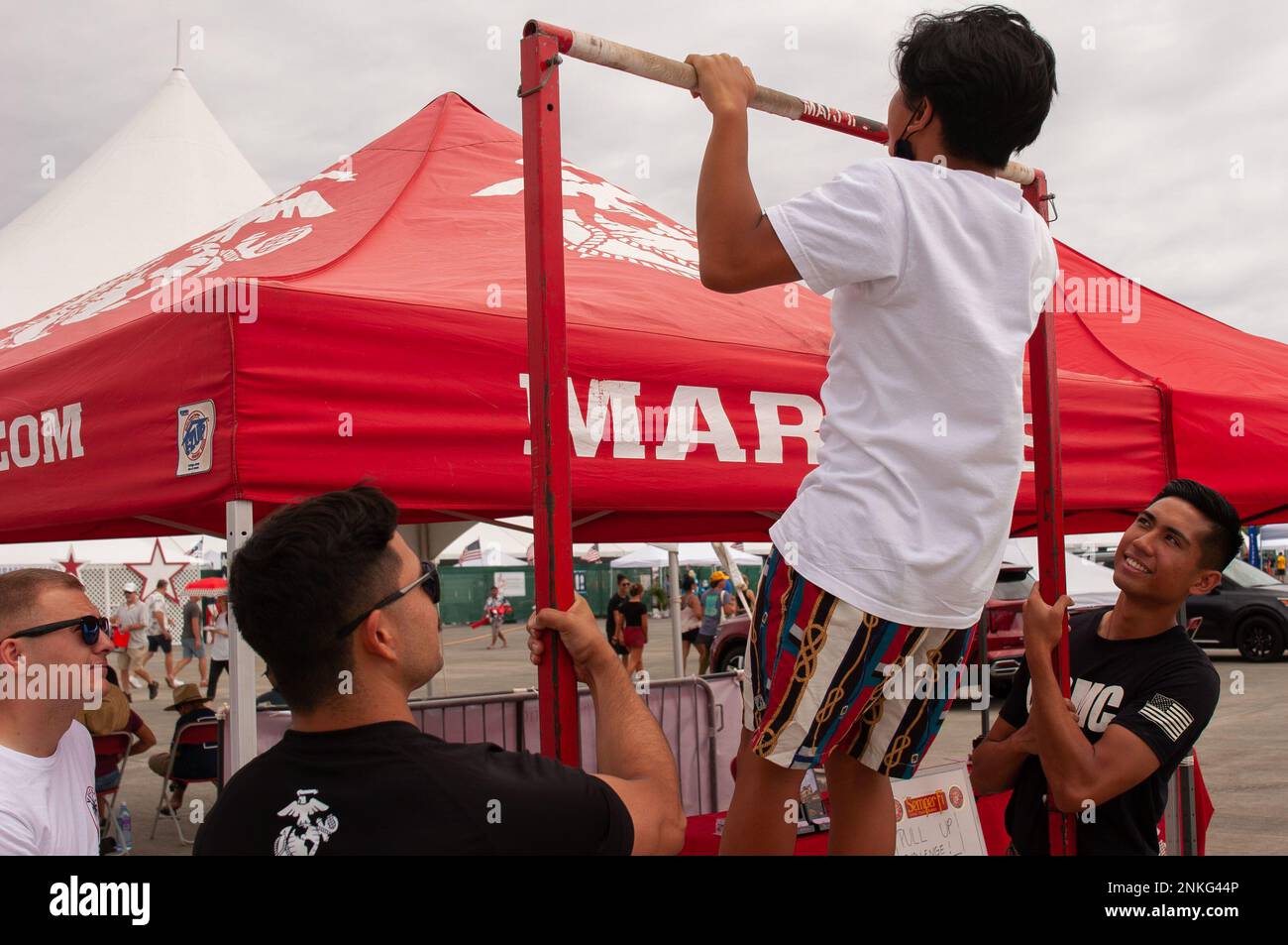 An airshow attendee attempts pull-ups at a Marine Corps recruiting vendor station during the 2022 Kaneohe Bay Air Show, Marine Corps Air Station Kaneohe Bay, Marine Corps Base Hawaii, Aug. 14, 2022. The air show provided an opportunity for MCBH to foster positive relationships with the local community, while providing a unique experience to the public. The Kaneohe Bay Air Show, which contained aerial performances, static displays, demonstrations and vendors, was designed to celebrate MCBH’s longstanding relationship with the local community. Stock Photo