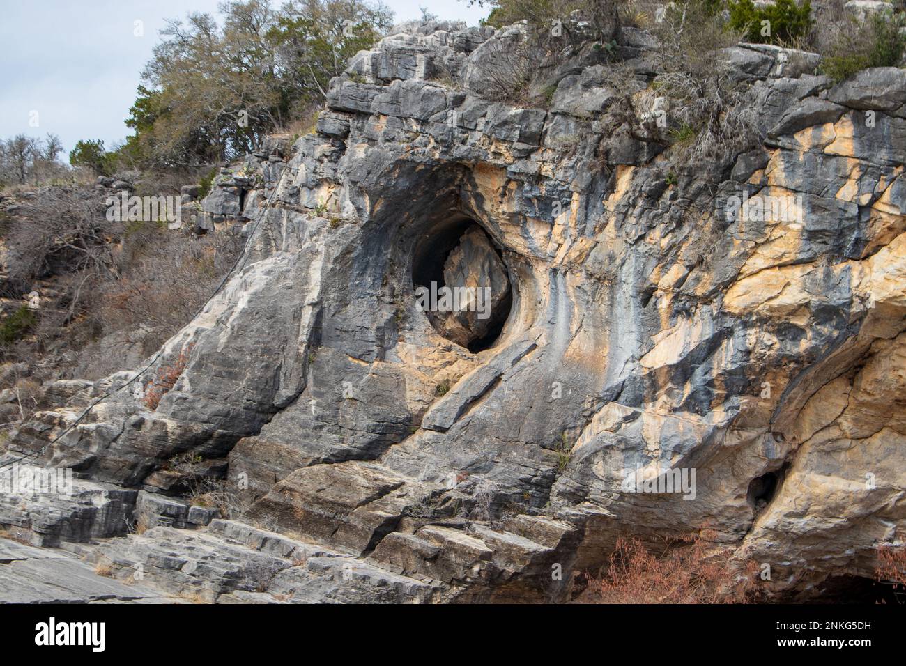 A wall of geological limestone formations creates a holeinone stone carving in Pedernales