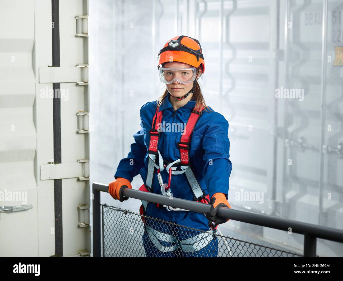Female worker climbing harness standing cargo container hires stock