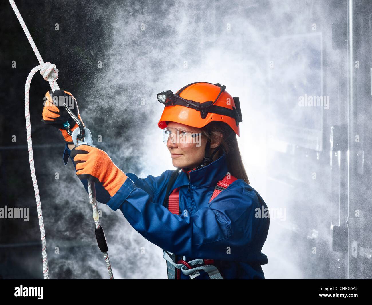 Female industry worker attaching carbiner to climbing rope Stock Photo ...