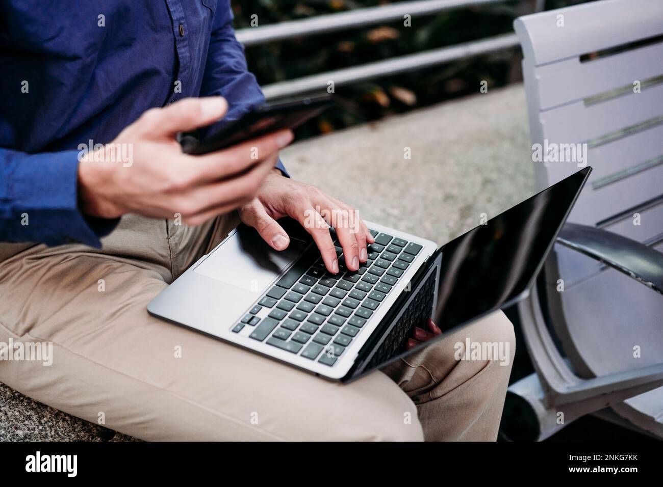 Businessman with smart phone using laptop Stock Photo