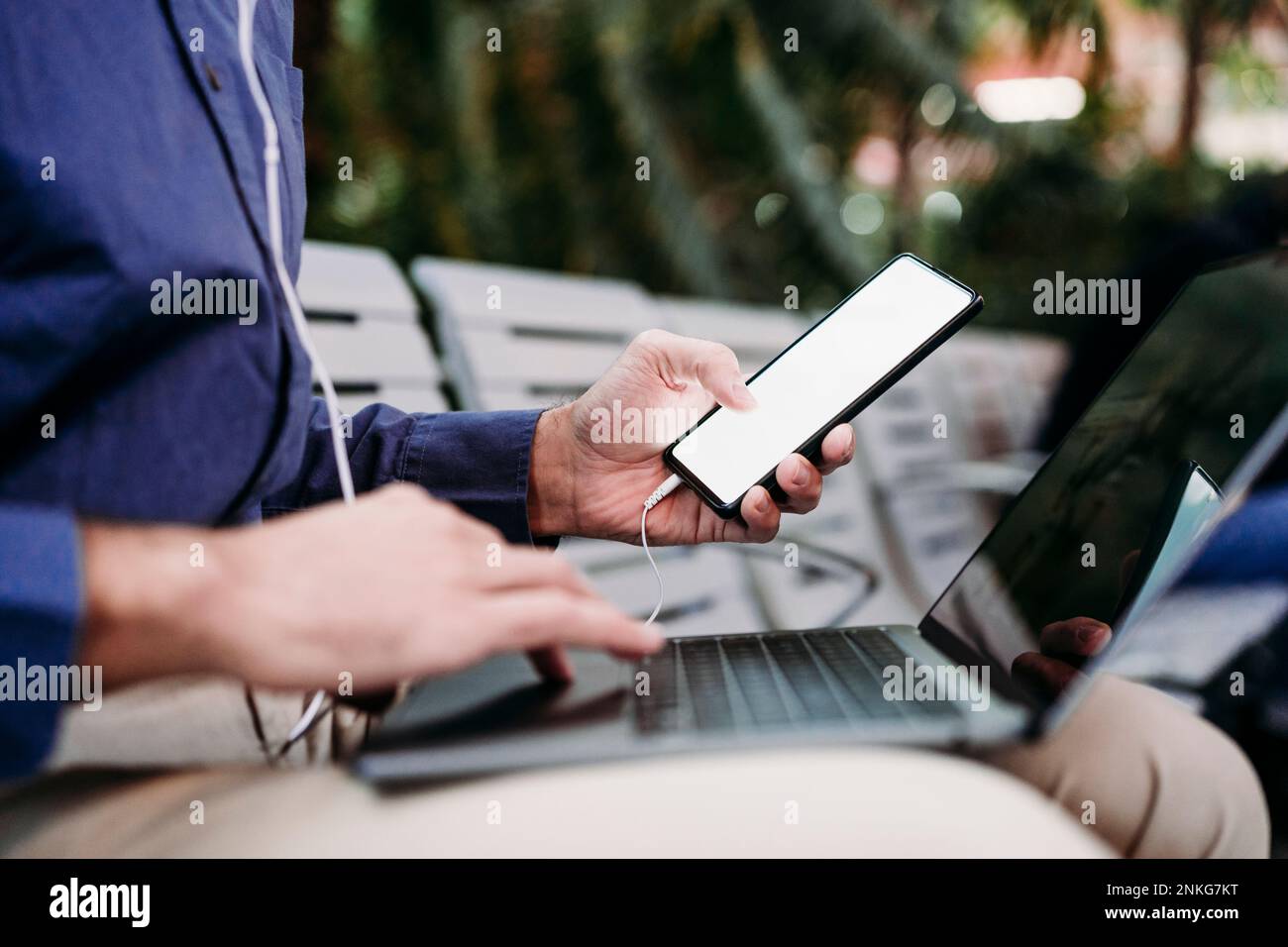 Young businessman with smart phone using laptop Stock Photo