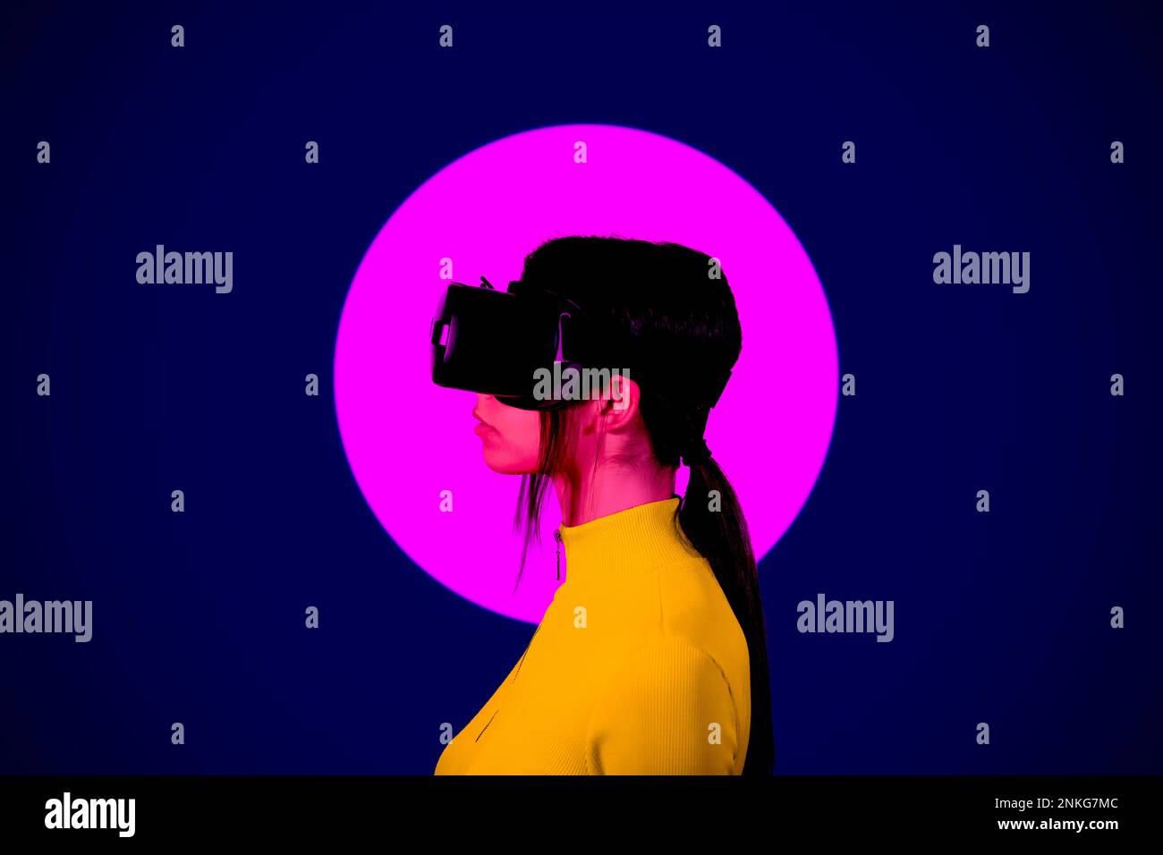 Young woman wearing VR Goggles by pink circle on black background Stock Photo