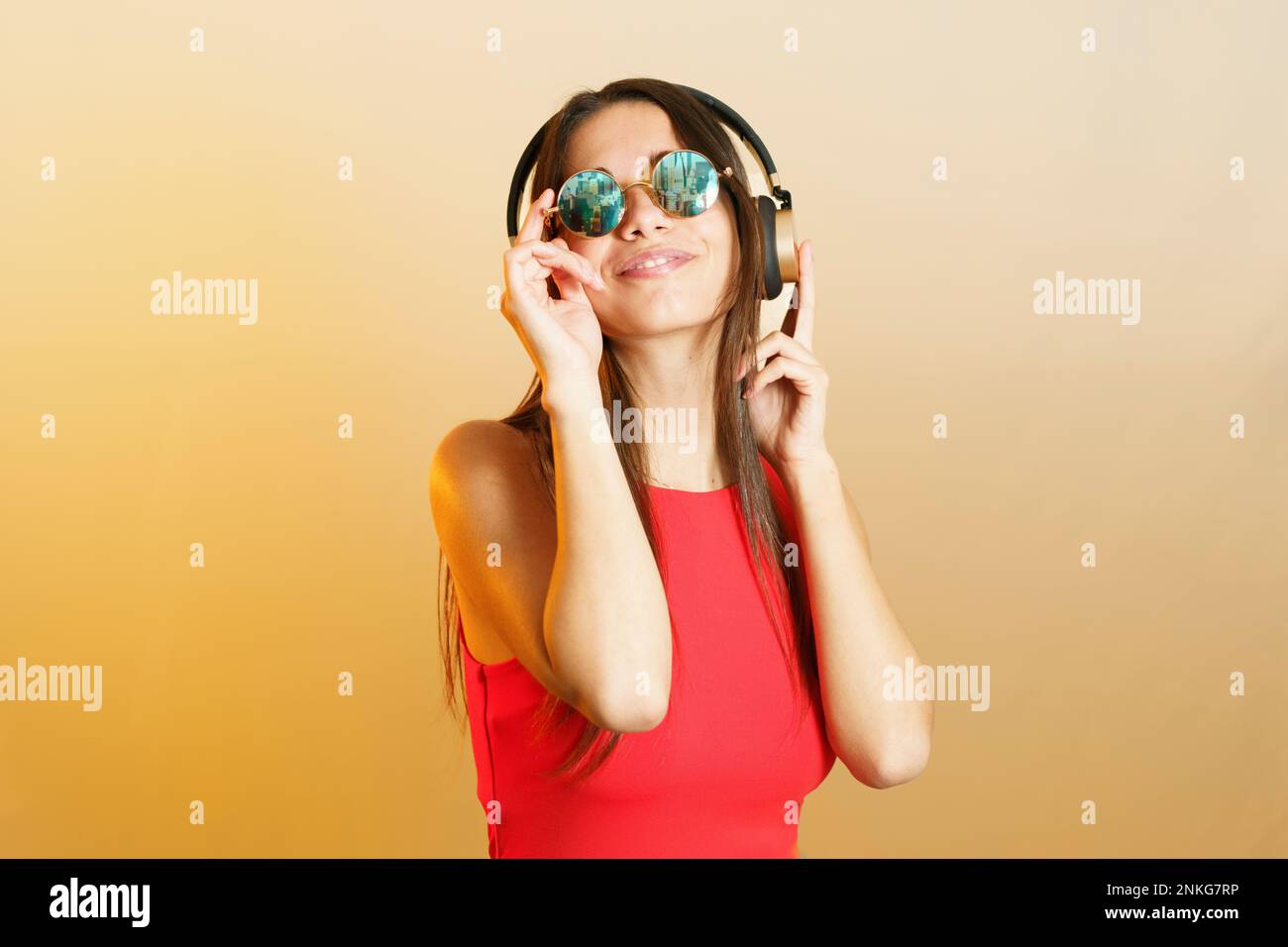 Smiling woman wearing steampunk sunglasses and listening music on headphones Stock Photo