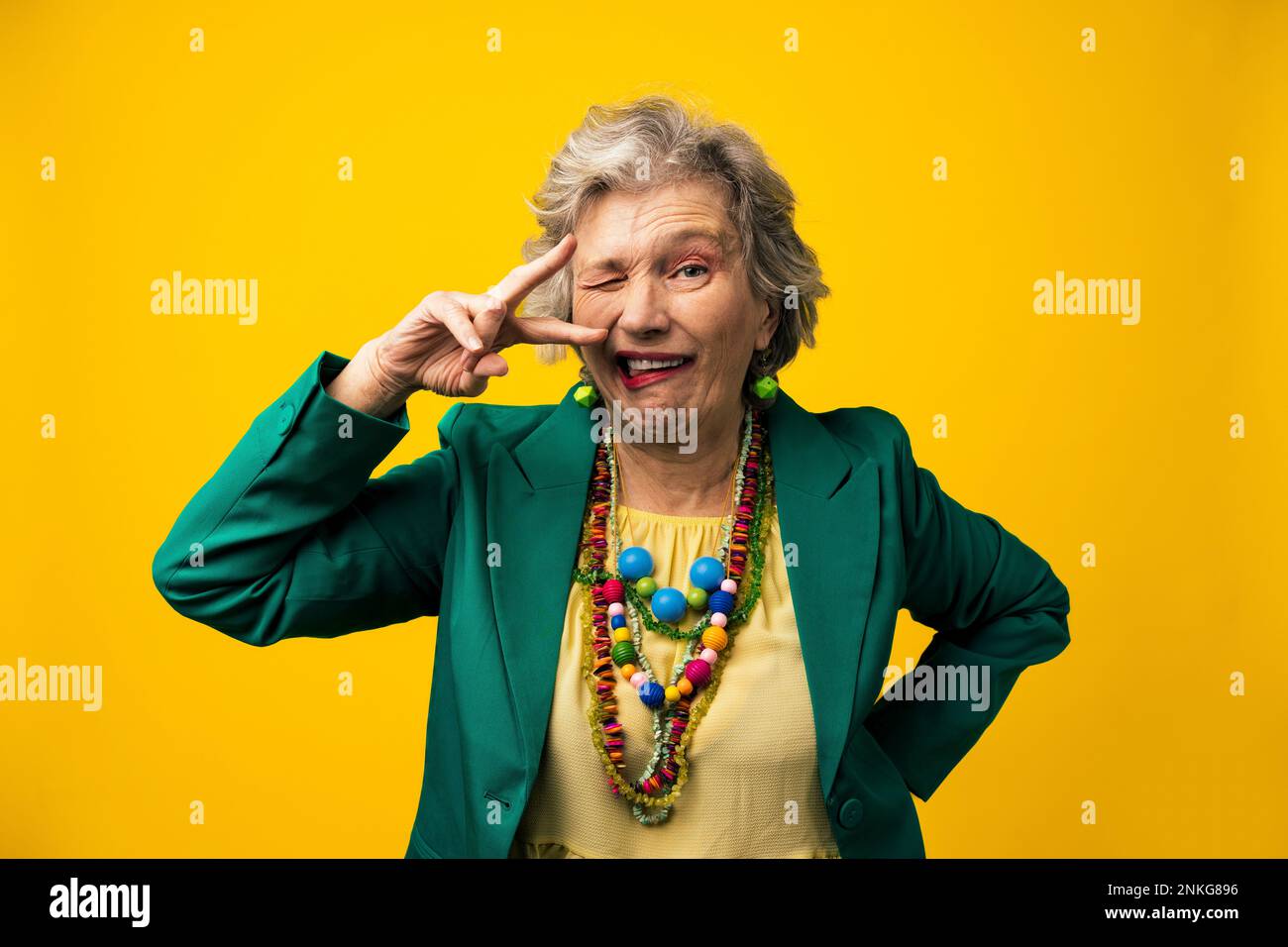 Senior woman with facial expressions against yellow background Stock Photo