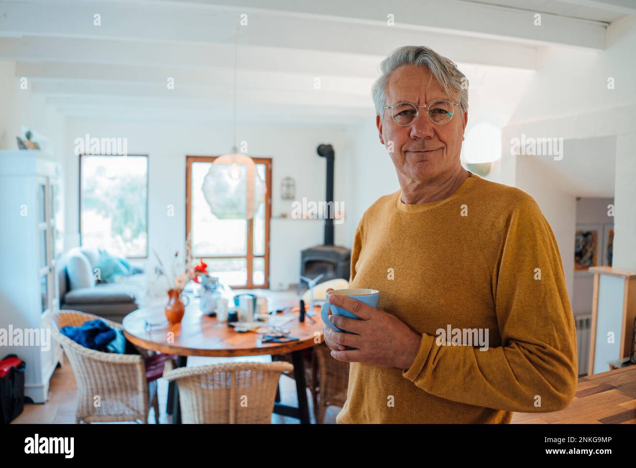 Smiling senior man standing with coffee cup at home Stock Photo