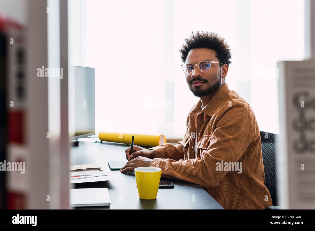 Businessman using graphics tablet sitting at desk Stock Photo