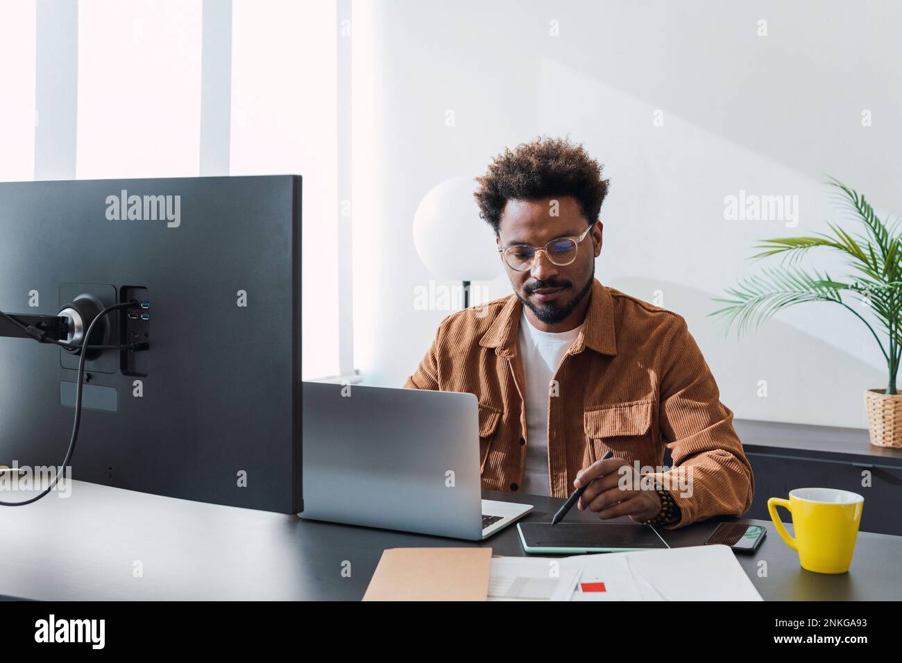 Businessman with laptop using graphics tablet in office Stock Photo