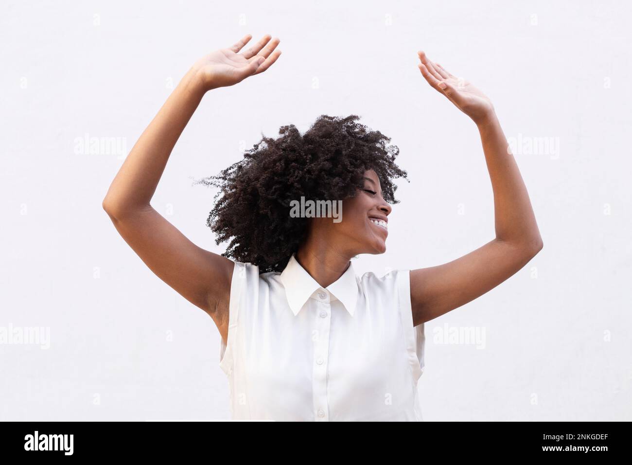 Happy woman with arms raised having fun against white background Stock ...