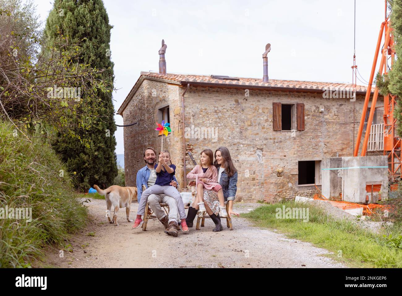 Happy family with dog sitting in front of house Stock Photo