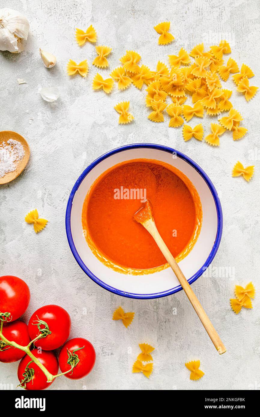 Tomato sauce with raw pasta kept on table Stock Photo