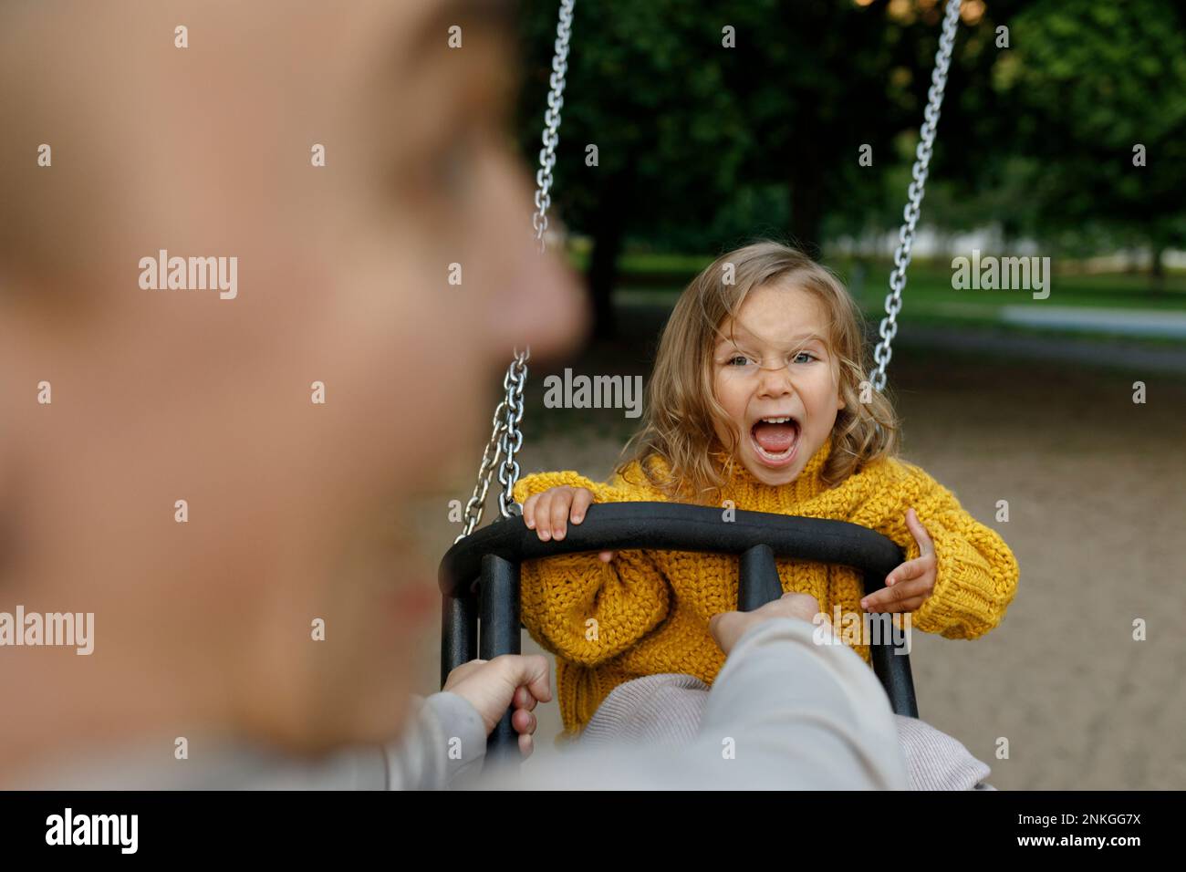 Father pushing daughter on swing at park Stock Photo