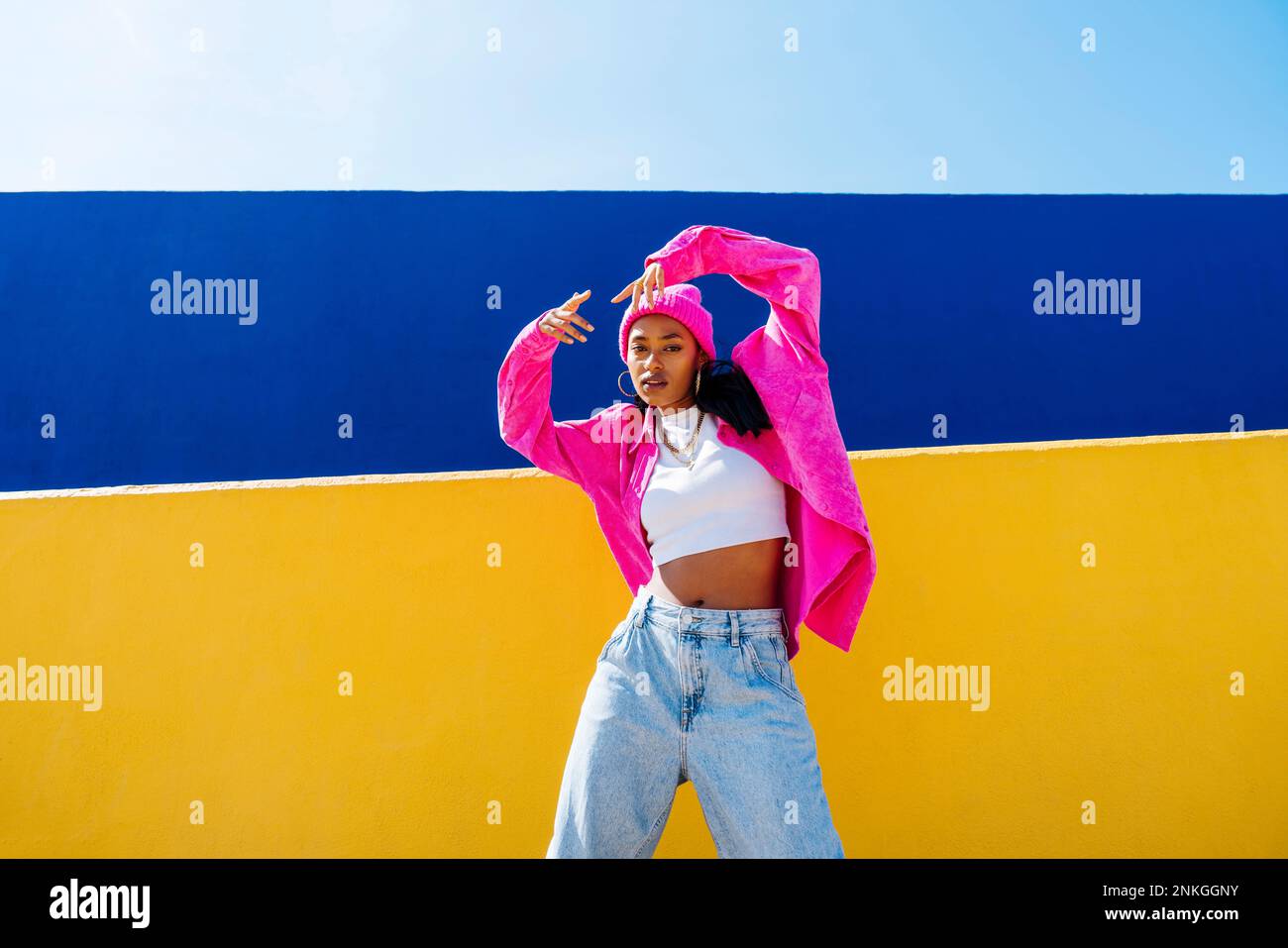 Young woman with cool attitude dancing in front of yellow wall Stock Photo
