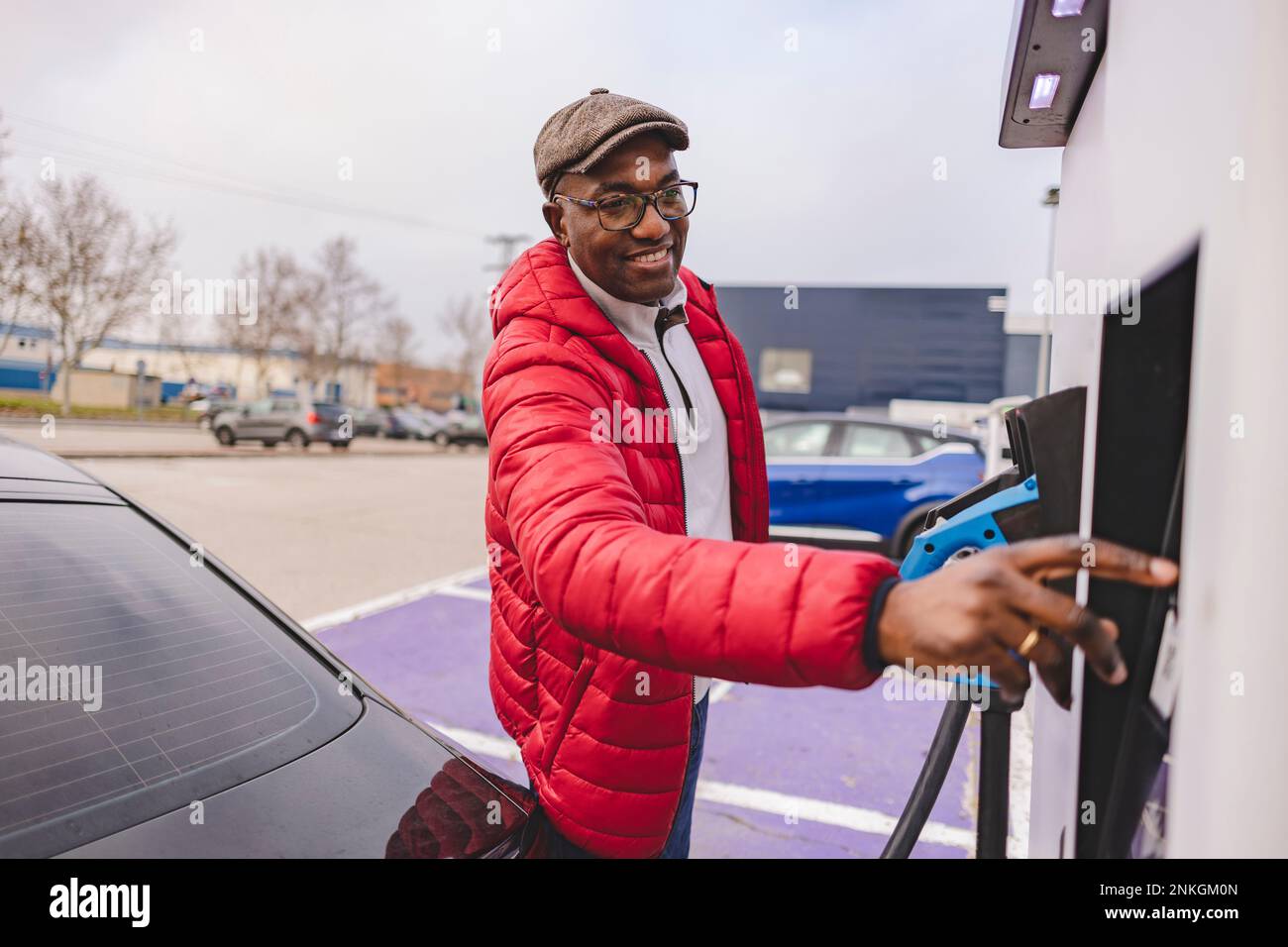 Smiling mature man using electric charging at station Stock Photo