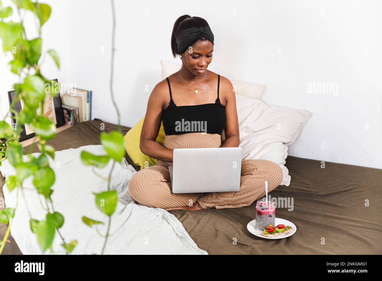 Smiling pregnant freelancer using laptop at home Stock Photo
