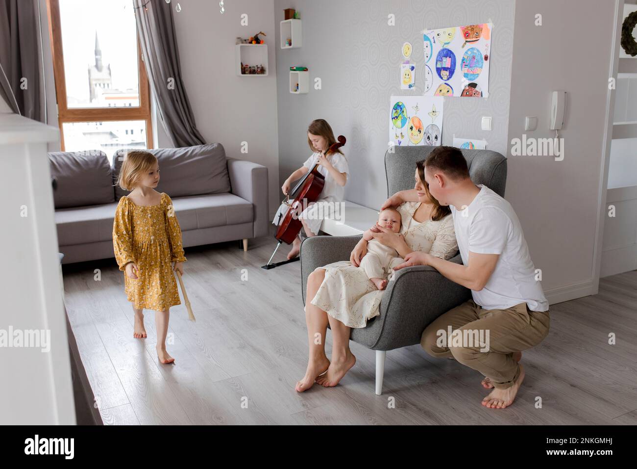 Parents holding boy with girl playing musical instrument in background Stock Photo