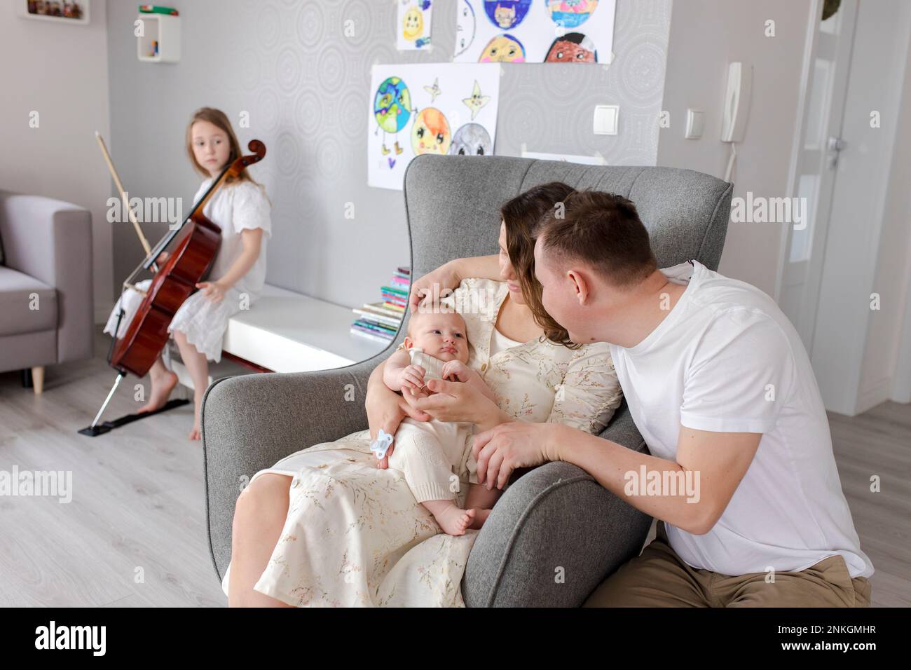 Parents holding baby boy with girl playing musical instrument in background Stock Photo